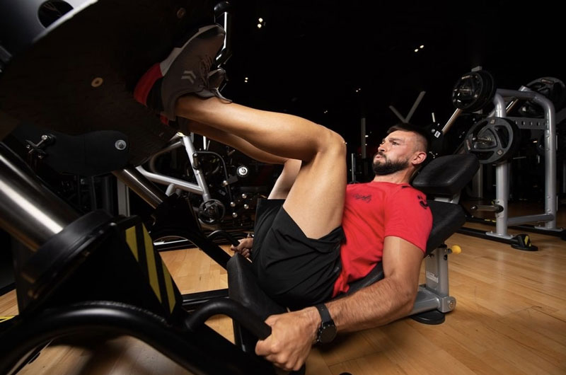 Una foto del entrenador realizando un ejercicio de prensa de piernas.